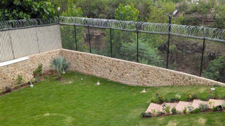 Singhara stone flooring in Pakistan for outdoor landscaping beside a natural stone garden wall